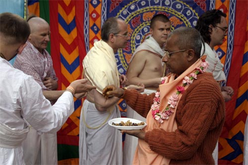 Sripad Bhagavat Maharaj giving out prasadam fruits from fire sacrifice after finishing yajna .